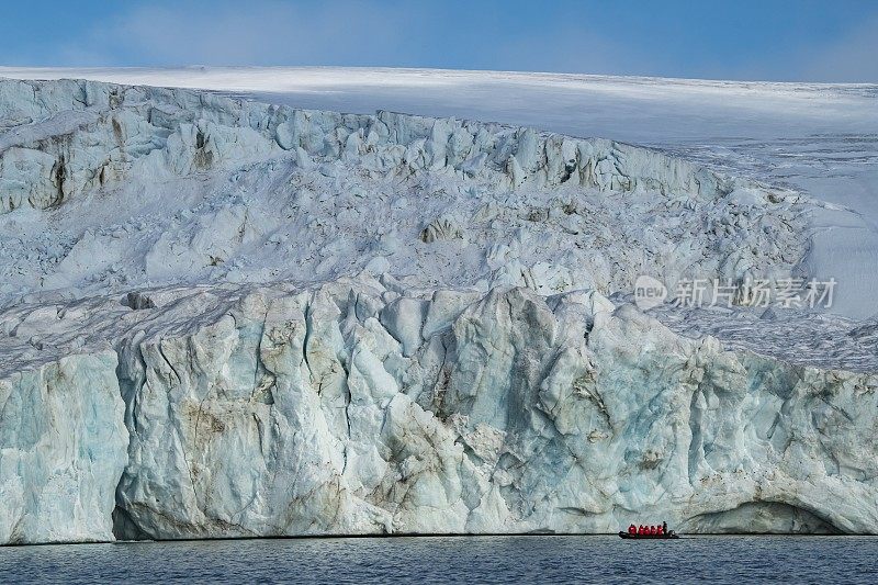 海神号(Poseidon Expeditions)探险游轮上的乘客在周围的环境中显得很渺小，他们乘坐一艘Zodiac摩托化橡皮艇来近距离观察巨大冰川的表面
